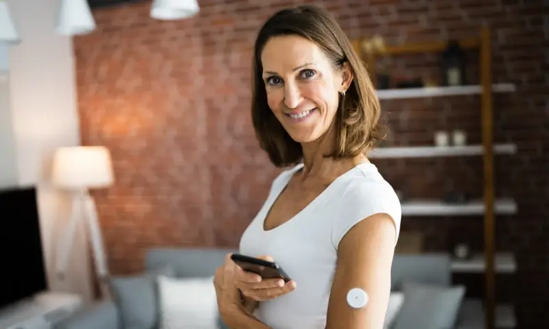 Smiling woman holding phone in modern living room