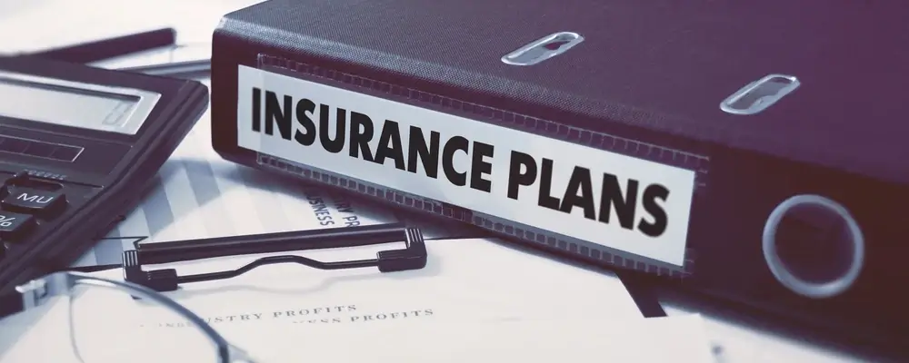 Insurance plans binder beside calculator on desk